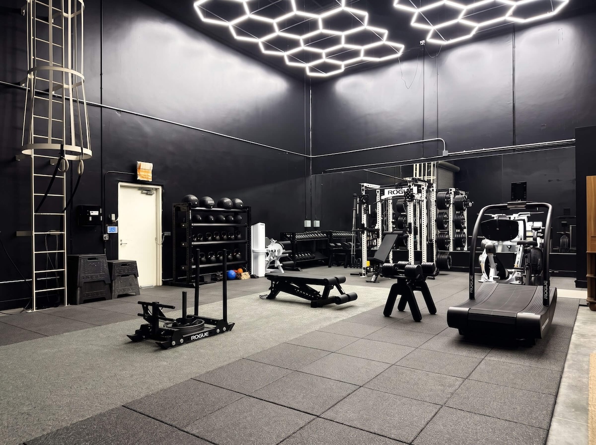 Open training floor with Rogue sled, medicine ball rack, and treadmill